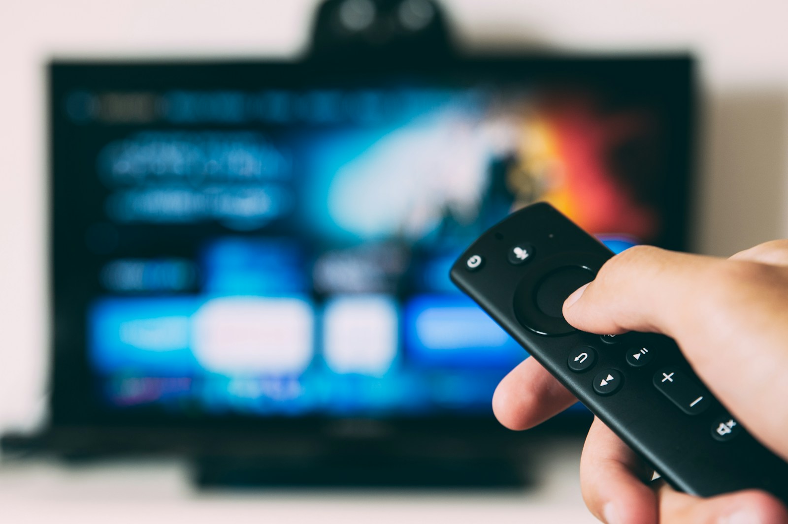 Comando de TV em frente a uma Smart TV para configurar IPTV português